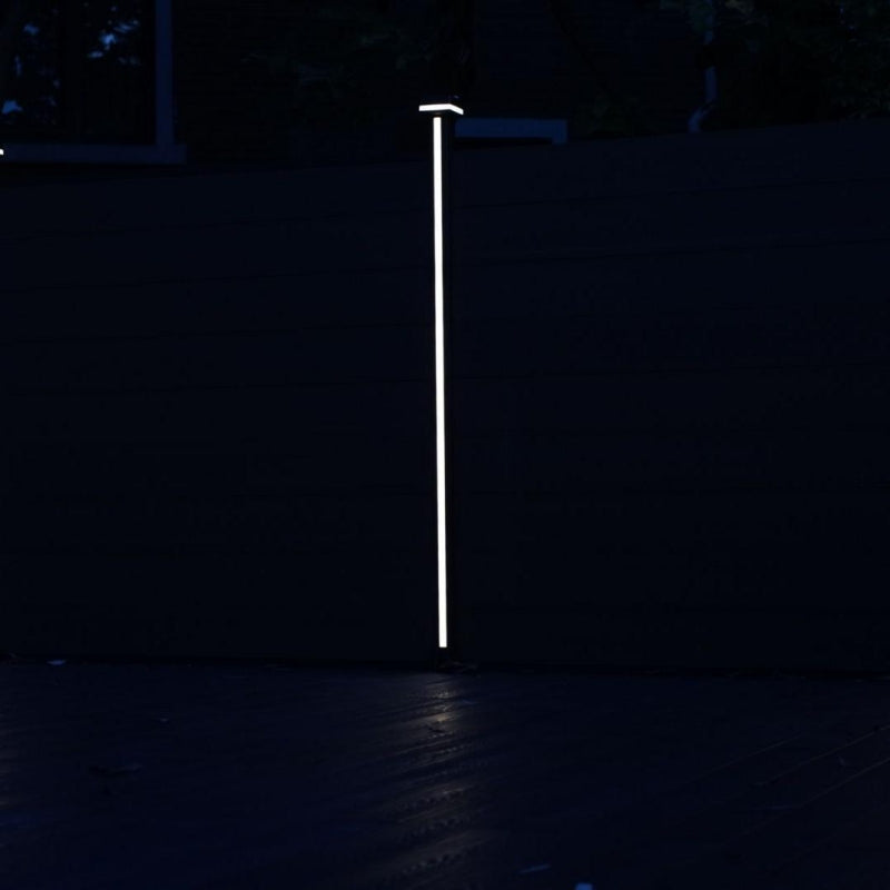 Vertical LED fence post light illuminating modern fence at night