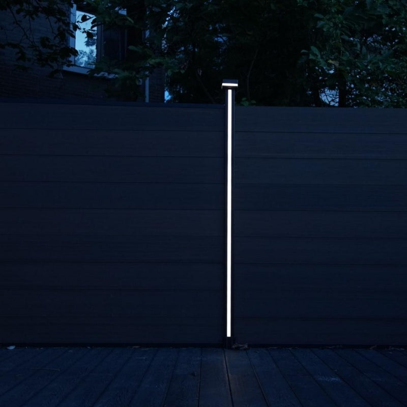 Vertical LED fence post light installed on composite privacy fence at night