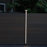 Vertical LED fence post light illuminating composite fence at night