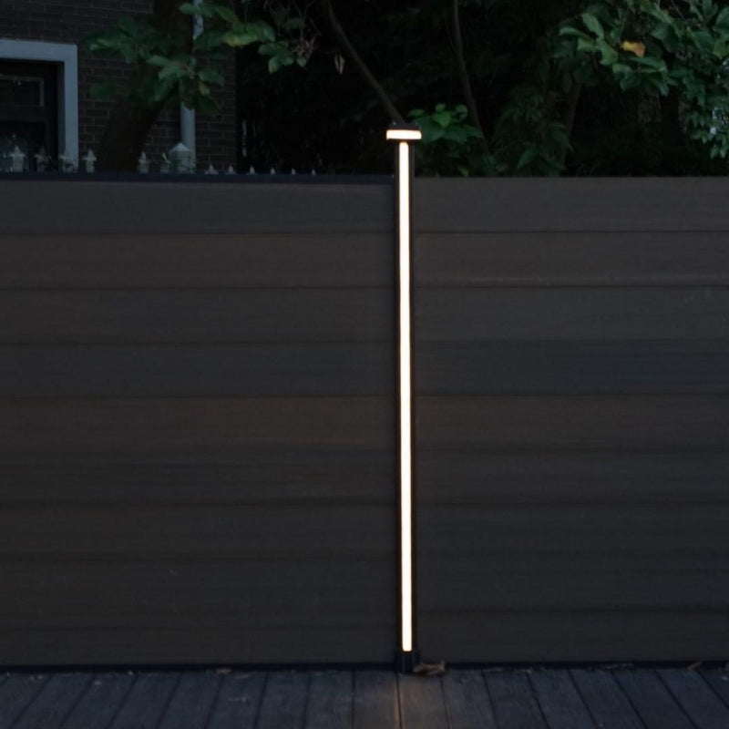 Vertical LED fence post light mounted on composite privacy fence at night