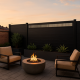 Black composite privacy fence with top ventilation panel in modern backyard patio at dusk